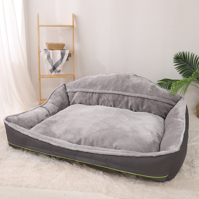 Gray pet bed on a light wooden floor with a white wall and plant in the background