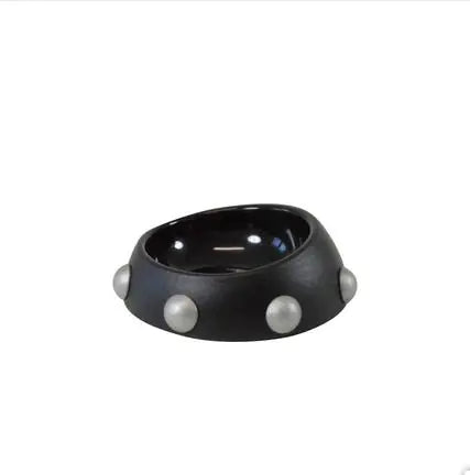 Black bowl with three white pearls on a white background
