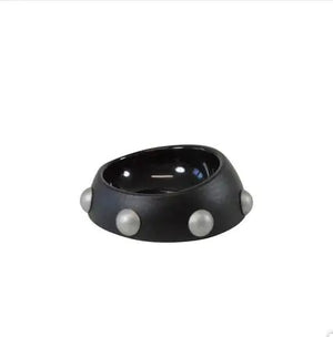 Black bowl with three white pearls on a white background