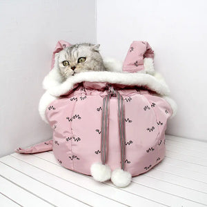 Cat sitting inside a pink pet carrier with white fur on a white surface.