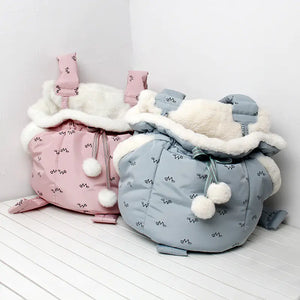 Pink and blue pet bags with white fur lining on a white surface.