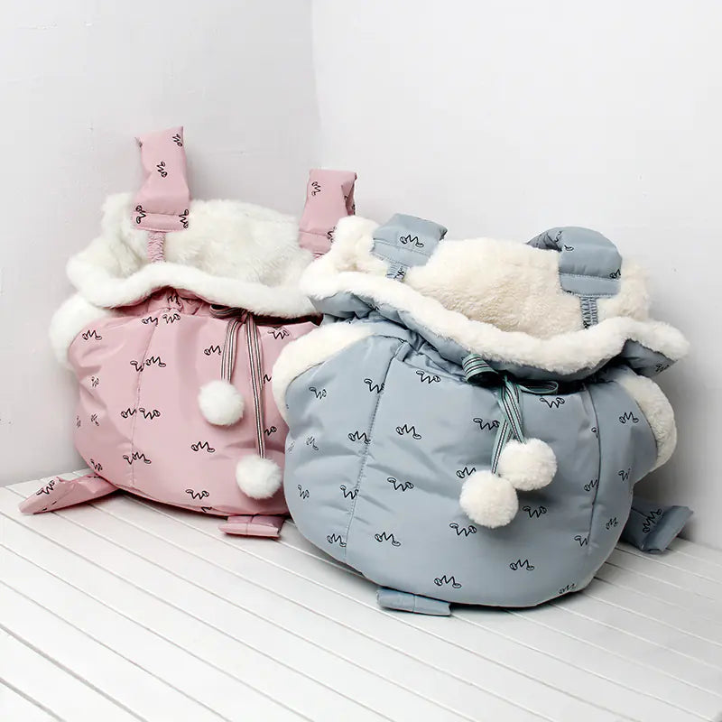 Pink and blue pet bags with white fur lining on a white surface.