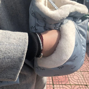 Close-up of a person wearing a light blue jacket with blue pet carrier with white fur.