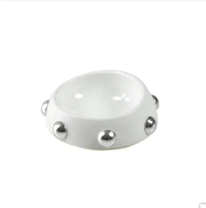 White ceramic bowl with silver studs on a white background